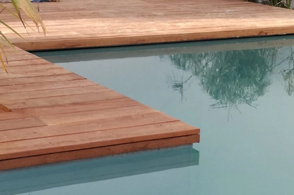 Infinity pool with under-coping overflow system and tropical-style wooden deck