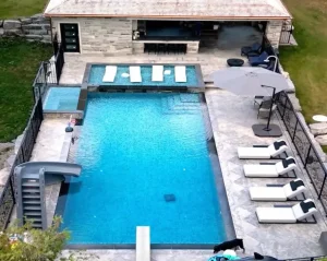 Aerial view of a zero-edge pool in Ontario featuring a cascading spa, a tanning shelf and a deep main basin