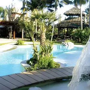 Bespoke Balinese-style infinity pool in Marbella with wooden bridge, tropical plants, and pavilion
