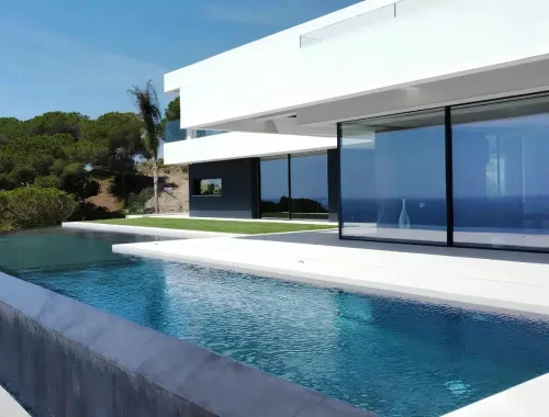 Infinity pool integrated into a contemporary hillside villa in Catalonia with panoramic sea views