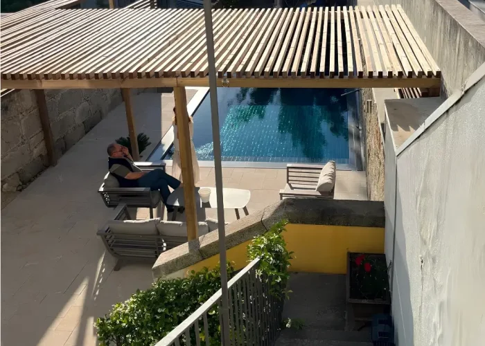 Daytime view of the infinity pool in Portugal with timber pergola, stone deck and upper terrace